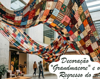 Uma fotografia de um átrio moderno e amplo, com paredes de betão, onde se destacam grandes colchas de patchwork coloridas suspensas no teto, criando formas onduladas. Ao fundo, duas pessoas caminham pelo espaço, e em primeiro plano vê-se uma mesa de centro de madeira com flores. No canto inferior direito, um grafismo branco contém o texto: "Decoração 'Grandmacore' e o Regresso do Patchwork".