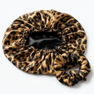 Touca protetora de cetim com padrão animal print para cabelos cacheados e lisos, isolada num fundo branco minimalista.