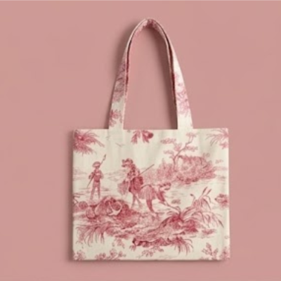 Bolsa tote em algodão toile de jouy vermelho cereja com alças, vista de perto sobre fundo têxtil rosa