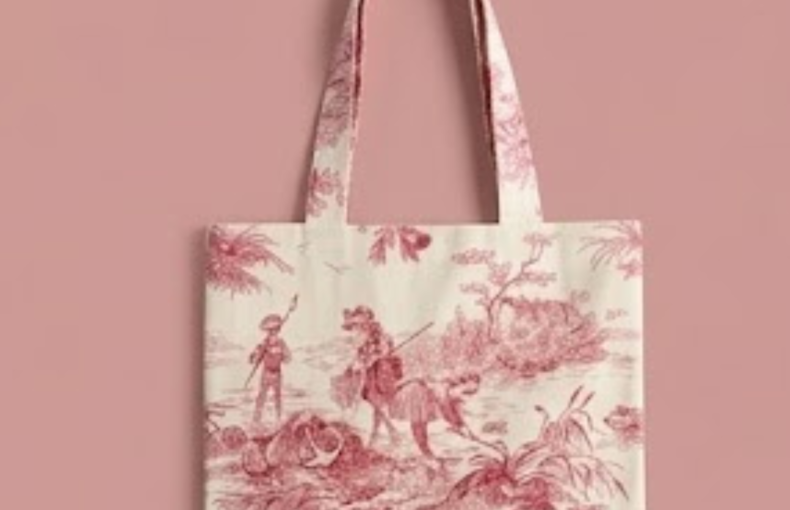 Bolsa tote em algodão toile de jouy vermelho cereja com alças, vista de perto sobre fundo têxtil rosa
